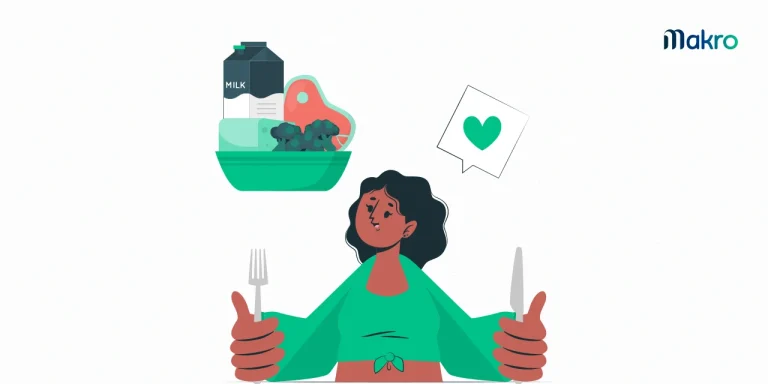 Uma mulher de cropped verde olha para alguns alimentos acima de sua cabeça. Há uma caixa de leite, um queijo, uma uva e uma carne dentro de uma cesta.