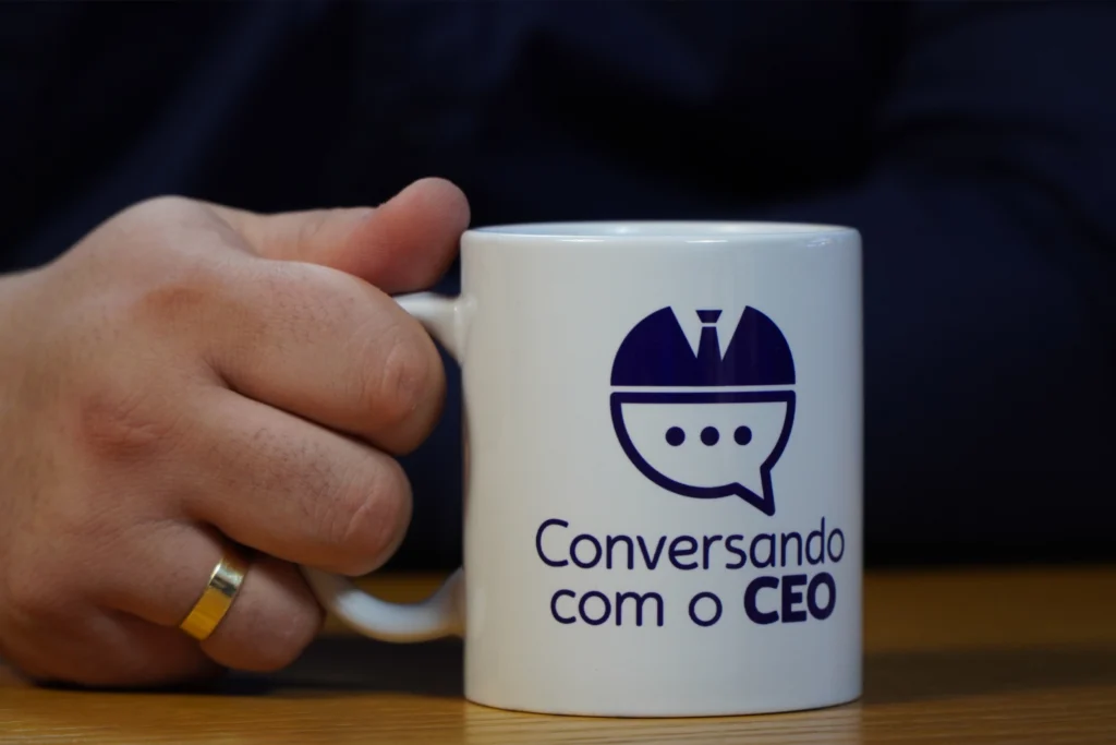 A imagem mostra uma mão segurando uma caneca com a inscrição 'Conversando com o CEO', promovendo um podcast da Makro.