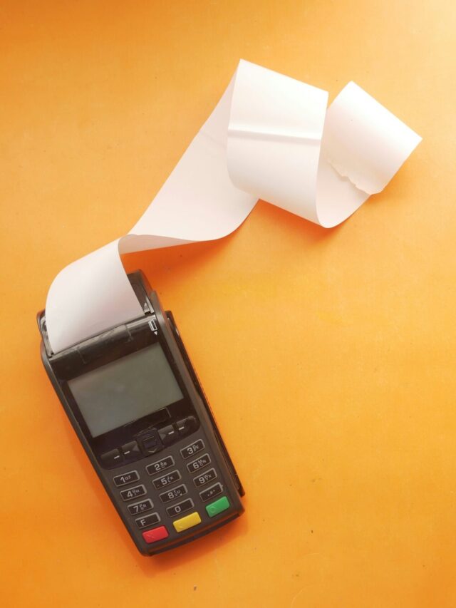 A imagem mostra uma máquina de cartão, emitindo cupom fiscal, buscando representar o conteúdo de situações de notas fiscais.