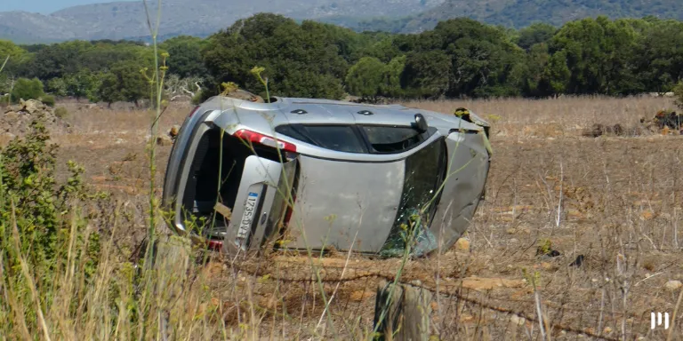 A imagem mostra um carro capotado em um lugar descampado. A imagem representa nitidamente um acidente de carro. A imagem ilustra o artigo sobre antigo DPVAT