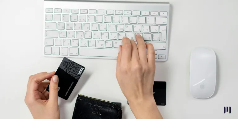 A imagem mostra uma pessoa com cartão de crédito na mão em frente ao computador pagando o DARF e DAS MEI através do cartão de crédito