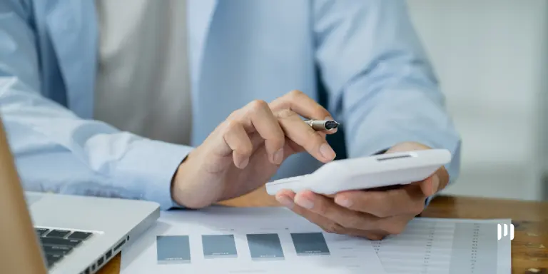Profissional calcula créditos de PIS/Cofins na transição para a CBS com documentos financeiros e calculadora.