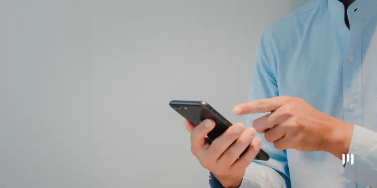 Pessoa utilizando um celular para consultar informações sobre o Cashback do IRPF e a restituição do Imposto de Renda.