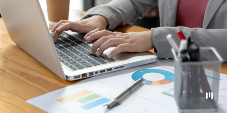 Profissional trabalha em notebook com gráficos sobre o Informe Técnico 2026.001 e a Reforma Tributária.