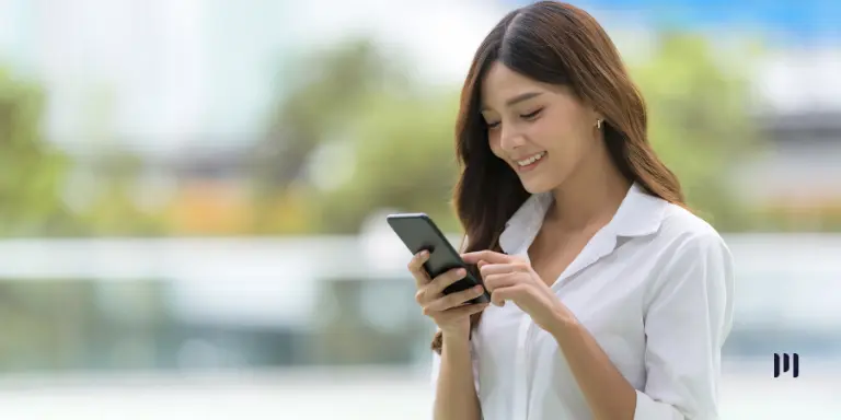 Mulher consulta pelo celular informações sobre o último lote do IR 2026.