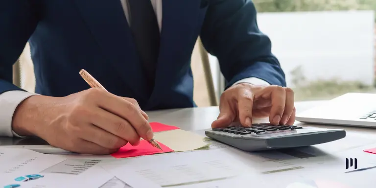 Profissional utilizando calculadora e fazendo anotações em documentos financeiros, representando as atualizações da Nota Técnica NFS-e.