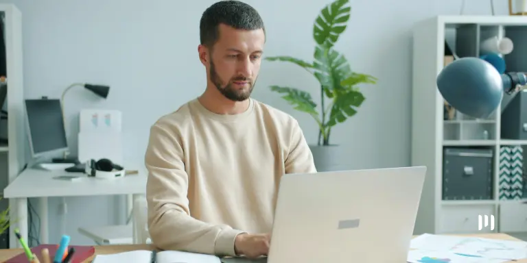 Homem trabalhando no notebook e consultando informações sobre os editais da PGFN.